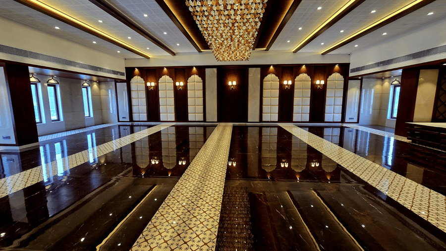 Spacious banquet hall with central aisle and ornate ceiling lights at Hotel Mumbai House, Digha, Airoli.