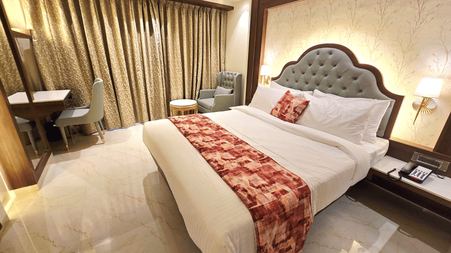 Comfortable bedroom with upholstered headboard and patterned runner at Hotel Mumbai House, Digha, Airoli.
