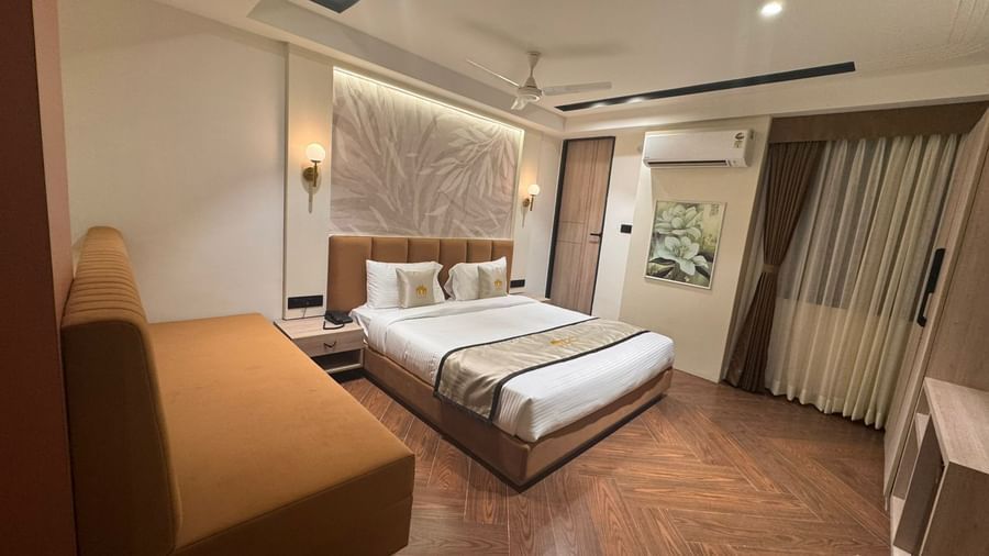 Bright and airy room at Hotel Mumbai House, Vijay Nagar, Indore, with a large bed, cosy sofa, and wooden flooring for a welcoming and homely feel.