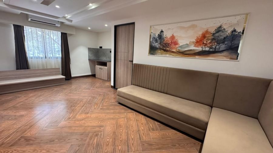 Spacious lounge-style seating with wooden flooring at Hotel Mumbai House, Vijay Nagar, Indore, perfect for unwinding or informal gatherings.