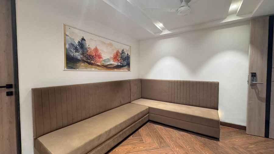 Stylish seating corner with modern sofa and wall art at Hotel Mumbai House, Vijay Nagar, Indore, offering a cosy spot for relaxation and comfort.