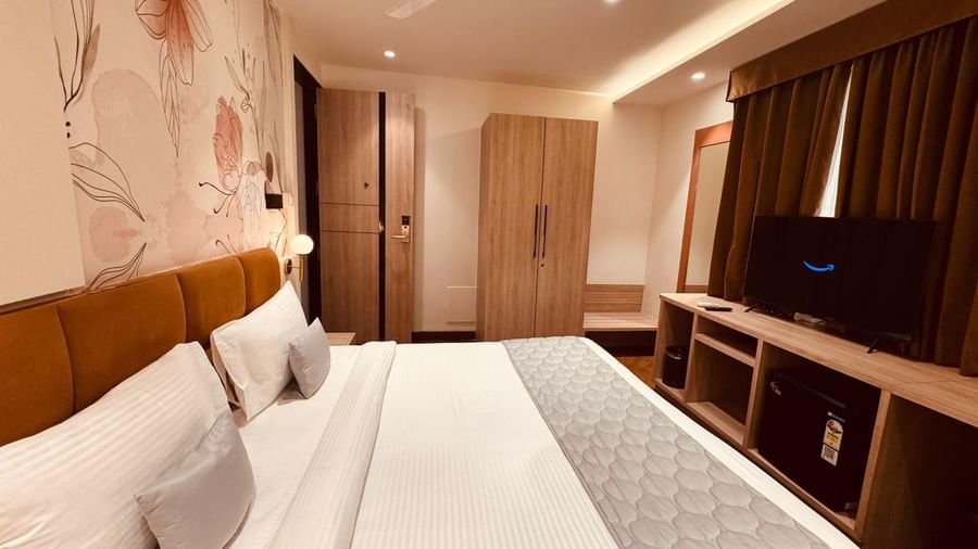 Modern bedroom at Hotel Mumbai House, Vijay Nagar, Indore, featuring a plush double bed, warm lighting, and wooden interiors for a restful stay.