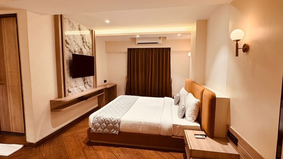 Spacious room at Hotel Mumbai House, Vijay Nagar, Indore, with a king-size bed, warm lighting, and wood flooring, perfect for leisure or business stays.