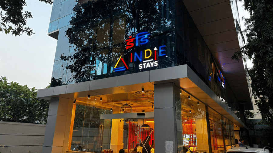 Exterior view of the glass-fronted entrance and lobby area showcasing modern architectural design at Indie Stays, NESCO Goregaon.