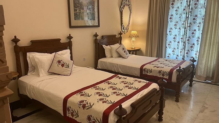A cosy twin bedroom with carved wooden decor, warm lighting, and traditional accents - Khas Bagh, Jaipur.