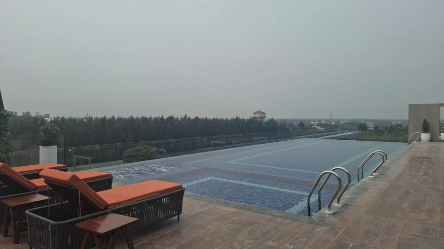 The rooftop swimming pool at Le ROI Digha Hotel, West Bengal, featuring a deck area with lounge chairs for relaxing.