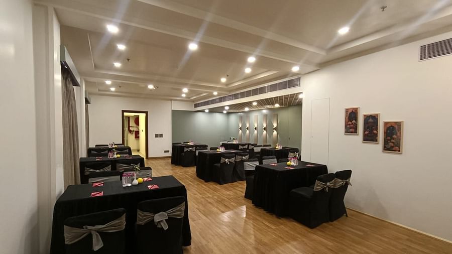 Conference room with rectangular tables covered with black satin covers and chairs under white ceiling lights at Lords Plaza Jaipur.