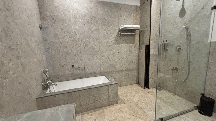 Large bathroom featuring a soaking tub and glass shower at Lords Riverside Resort, Muduba - Shivamogga