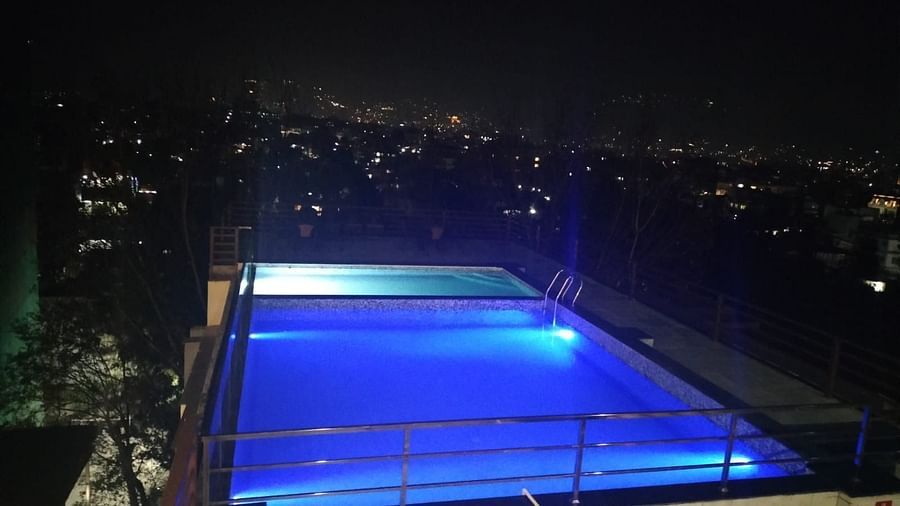 Night view of stairs leading down to the illuminated swimming pool with city lights in the backdrop at Mandala Norling Lords Prime in Kathmandu.