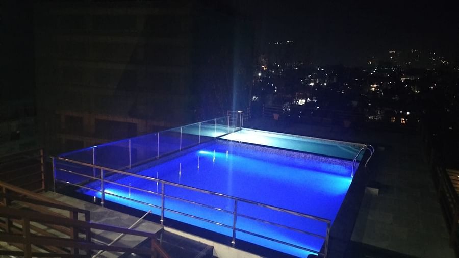 Night view of stairs leading down to the illuminated swimming pool with city lights in the backdrop at Mandala Norling Lords Prime in Kathmandu.