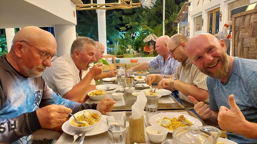 A side shot of multiple people having food at a dining table