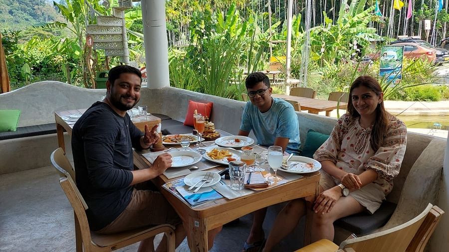 Dining scene - outdoor diner with three tables in view and three people posing for the camera, seemingly happy with the food and ambience.