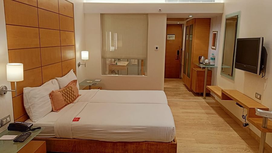 Image of twin beds in the executive twin room at our hotel featuring a flat screen television, bed side table, mirror, and other furniture. | Mirage Hotel