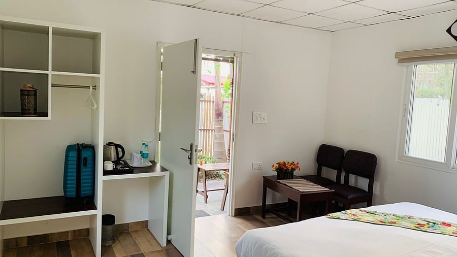a double bed with a bed runner on it and two chairs and a table inside one of the rooms - Neer Ganga Resorts