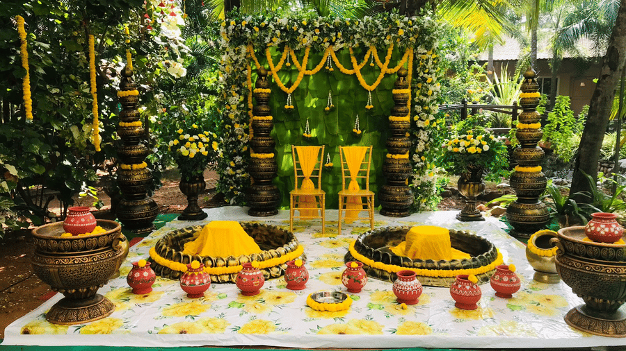 Decorative stage with floral arrangements, brass pots, and colourful backdrop at Paradise Lagoon Resort, Udupi.