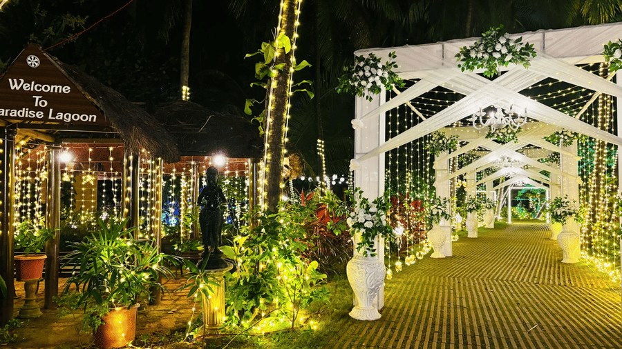 Pathway decorated with lights, flowers, and greenery at Paradise Lagoon Resort, Udupi.