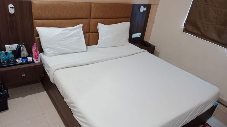 Top view shot of  double bed in the Deluxe Room at Pravasa Ahmedabad with bed side tables on either side of the bed.