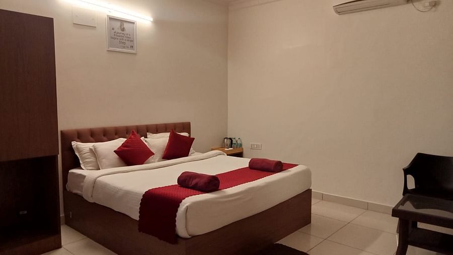 A side view of the bed with plush bedding along with a chair in the bedroom | Vistar Resort, Bengaluru