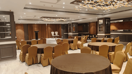 A bright meeting room with round tables, gold-coloured chair covers, and elegant recessed ceiling lighting - Skkylight Lords Inn, Nanded