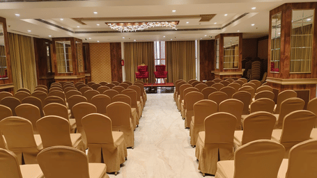The Raj Darbar event space featuring formal banquet seating and wooden wall panelling under warm interior lighting - Skkylight Lords Inn, Nanded