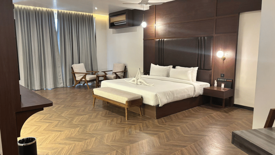 Spacious king bedroom with wooden flooring at Lords Riverside Resort, Muduba - Shivamogga