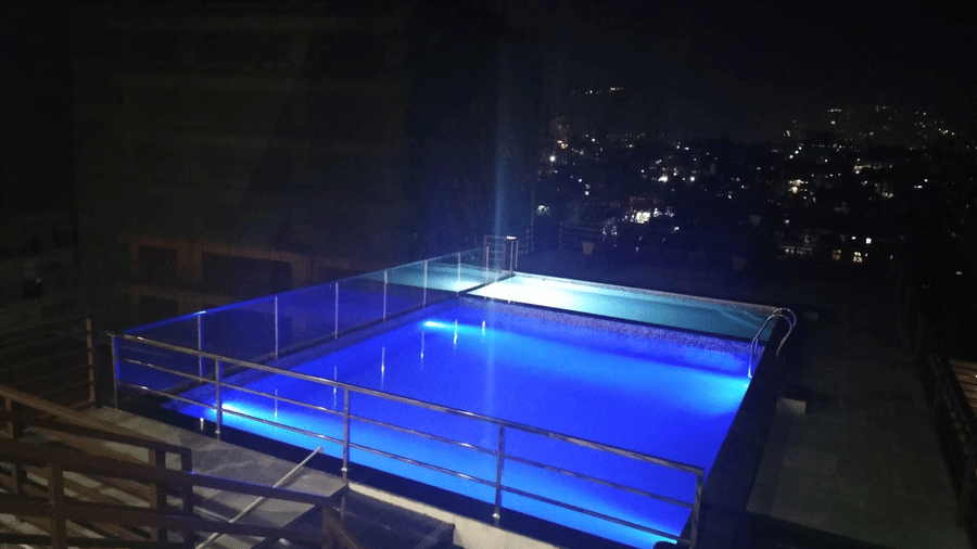 Night view of stairs leading down to the illuminated swimming pool with city lights in the backdrop at Mandala Norling Lords Prime in Kathmandu.