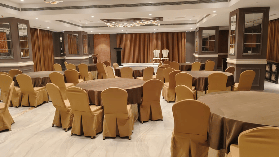 An event space with round tables, gold-toned seating, and elegant wood panelling under warm lights - Skkylight Lords Inn, Nanded