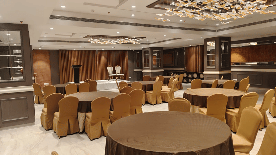 A bright meeting room with round tables, gold-coloured chair covers, and elegant recessed ceiling lighting - Skkylight Lords Inn, Nanded