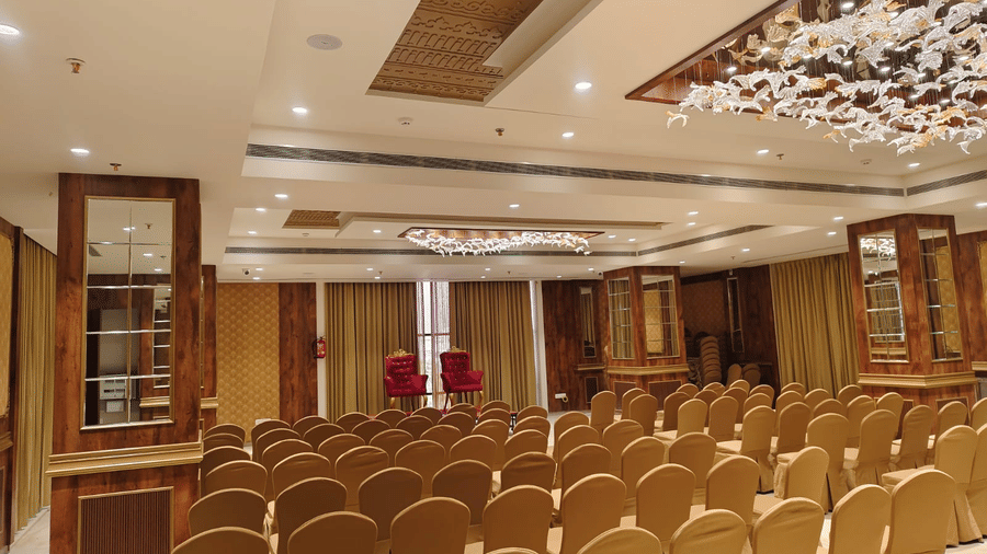 An expansive Raj Darbar banquet hall featuring rows of gold-clothed chairs and a red-carpeted centre aisle - Skkylight Lords Inn, Nanded