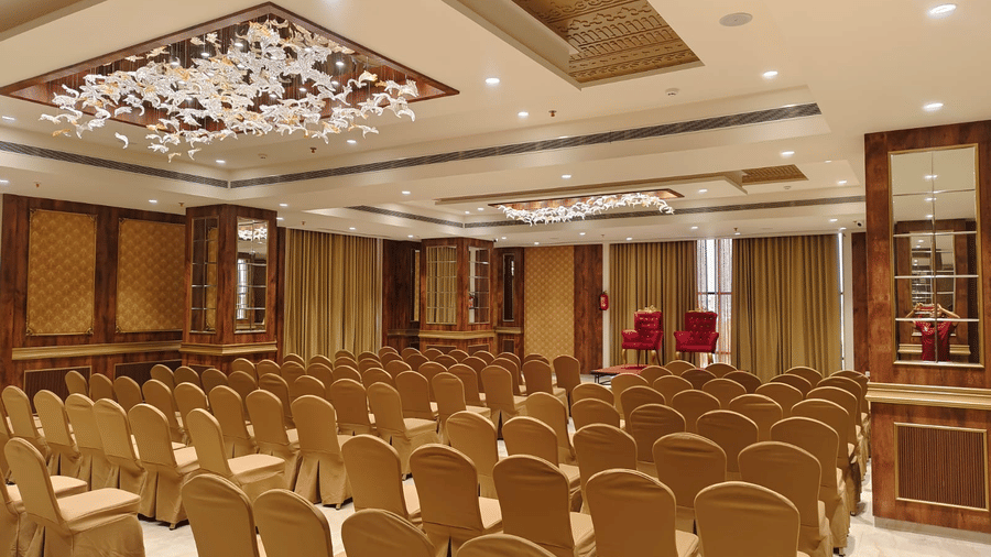 A formal event setting within the Raj Darbar hall showing ornate ceiling lights and wooden wall panelling - Skkylight Lords Inn, Nanded