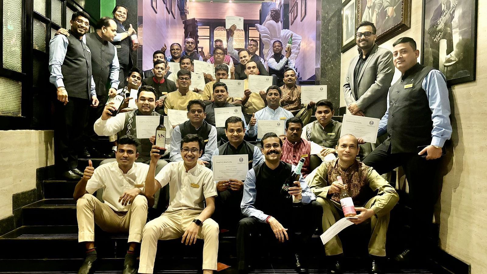 Group of staff members celebrating achievements with certificates and awards inside a hotel.