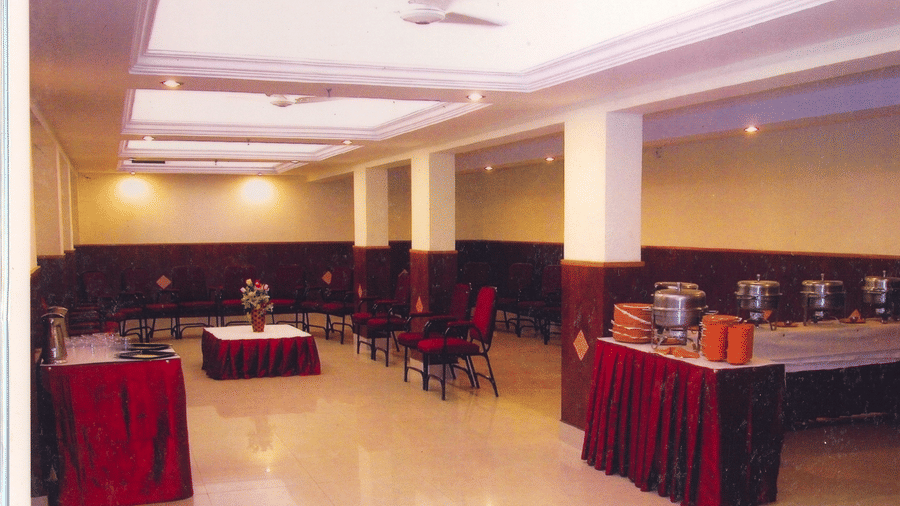 Indoor banquet facility showing a buffet serving counter setup with dark red fabric skirting - Hotel Pandian
