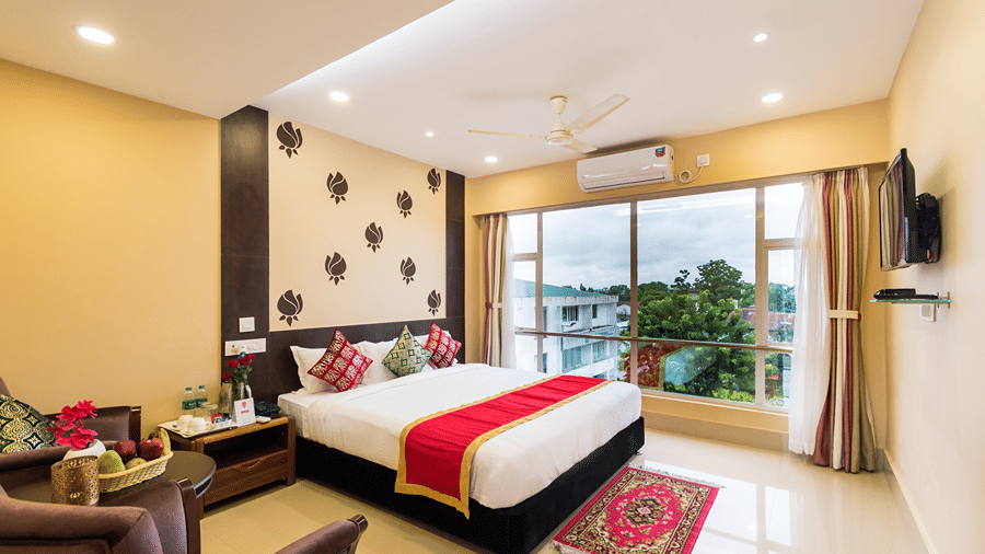 Super Deluxe Room at Central Courtyard Boutique Hotel, Siliguri, featuring a plush bed with a carpet at the foot next to a large window with view