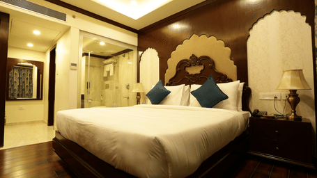 A bedroom at Comfort Inn Sapphire by Eastlynn Collections, Jaipur with king size bed, headboard design, side tables, lamps, and wooden flooring.