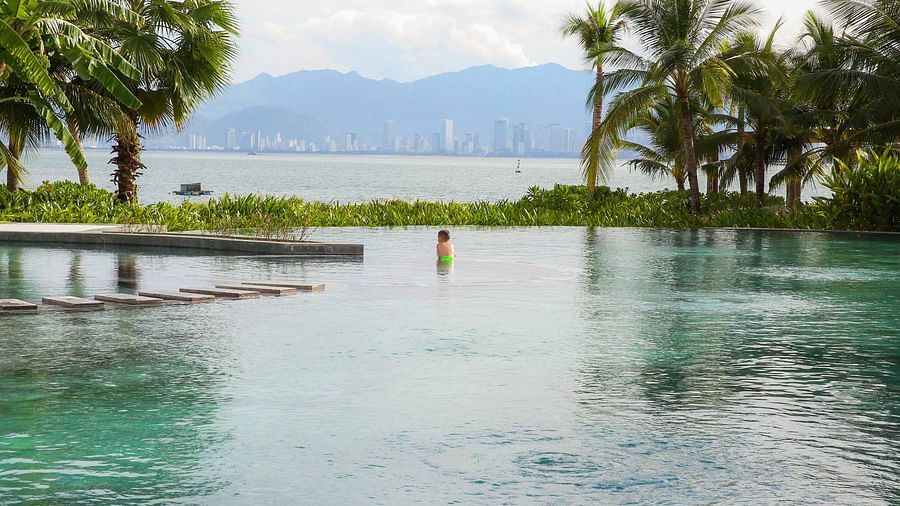 An image of a pool and a river bordered by palm trees - Alibu Resort Nha Thrang
