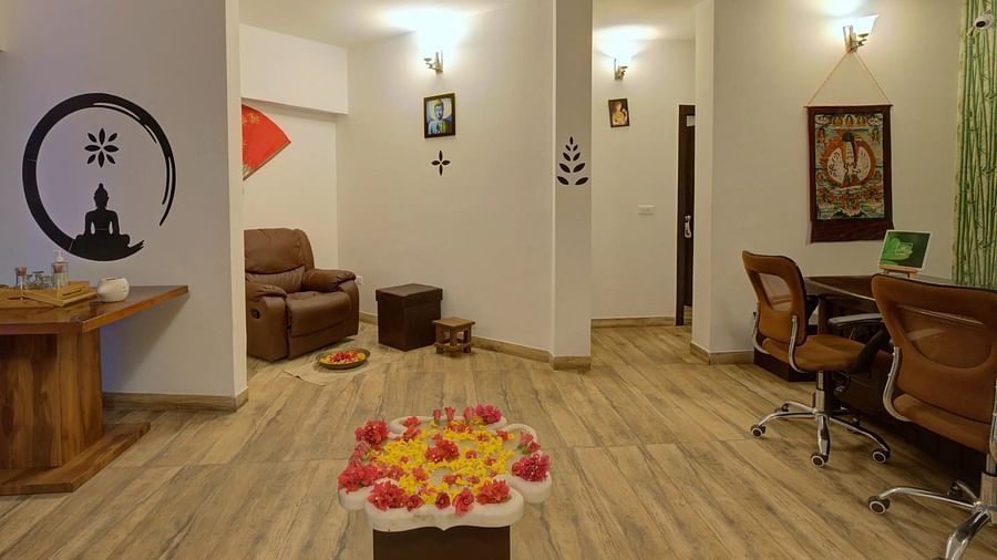 Modern interior with wooden floors, Buddha silhouette, lounge chair, desk, and a flower arrangement.-Bamboo Saa, Udaipur