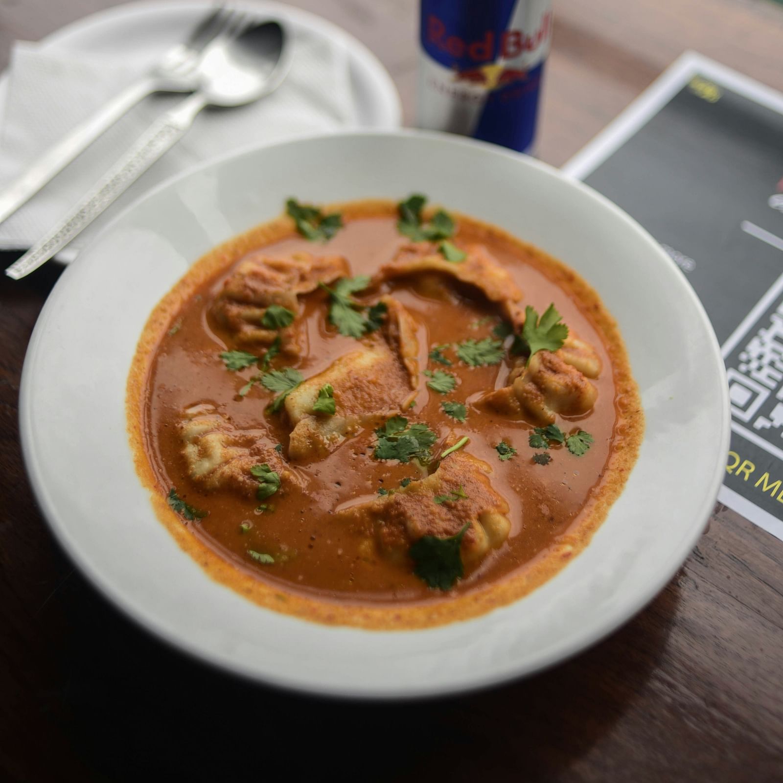 A plate of steamed momos in a curry.