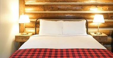 A room with a double bed and side tables with night lamps placed on it -Shaver Lake Village Hotel.