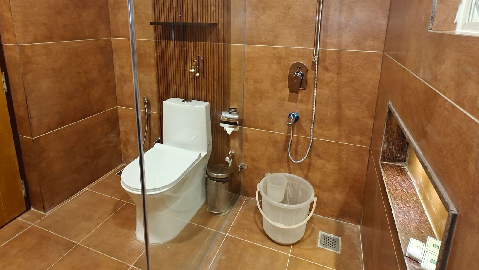 Deluxe Family Room bathroom at Woodstock Resorts, Coorg with modern fittings, glass shower, toilet, sink, and stylish wooden accents.