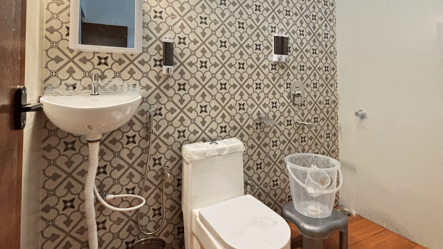 A brightly-lit bathroom featuring a commode along with a wash basin beside it at WOW Naturefull Resorts, Yercaud.