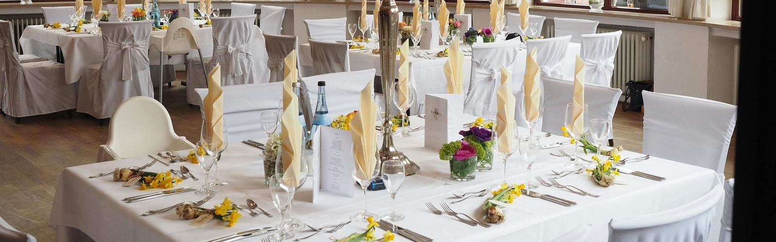 A restaurant depicting seating arrangement with cutlery and decorative items on the table