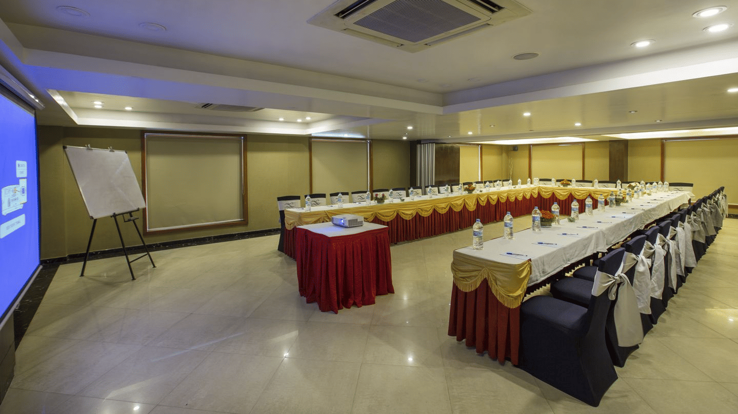 A long conference table draped in red and white, set for a formal meeting - The Citrine, Bangalore