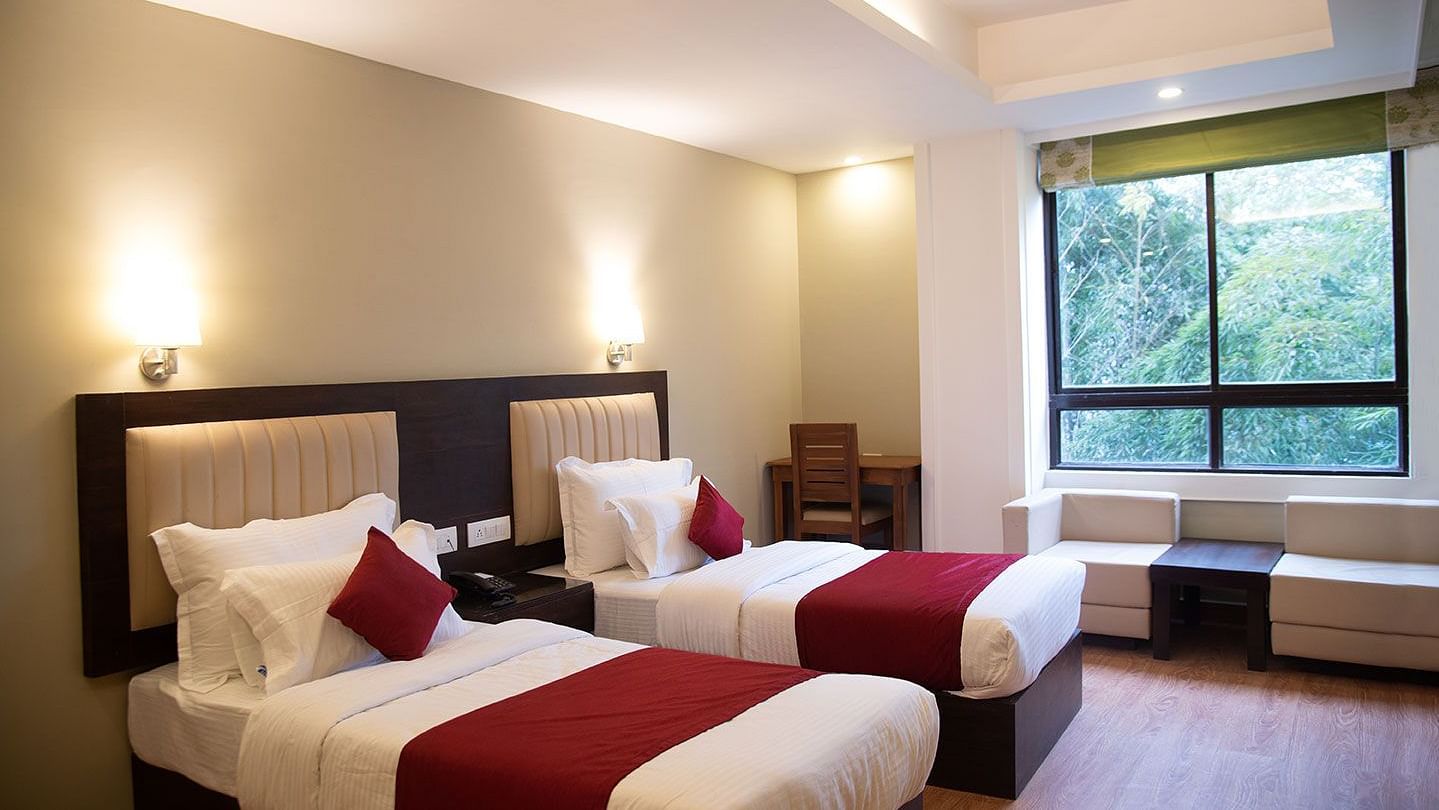 A hotel room in Gangtok featuring twin beds, warm lighting, and a window offering stunning views - Summit North Star, Gangtok