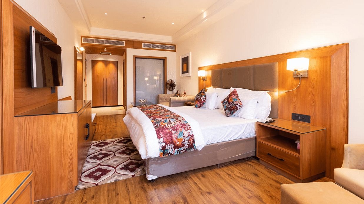 Elegant hotel room with a king size bed, wooden furnishings, a flat-screen TV, and warm lighting - Clarks Inn Express, Ludhiana