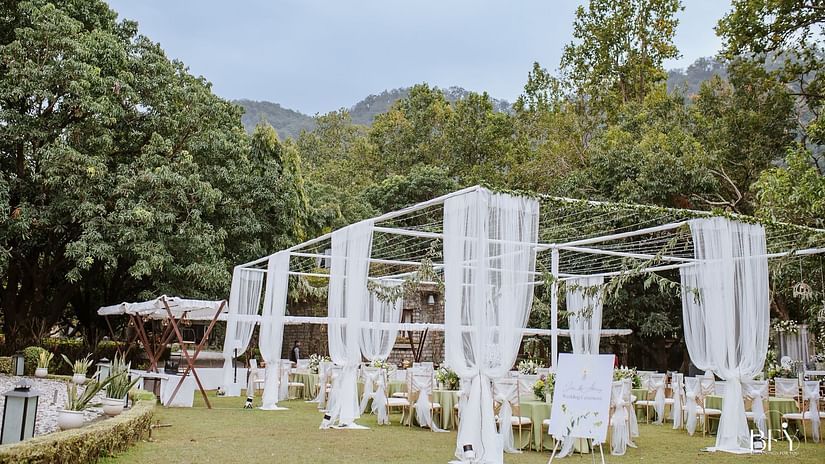 Elegant wedding setup with white curtains surrounded by lush greenery in a beautiful outdoor venue
