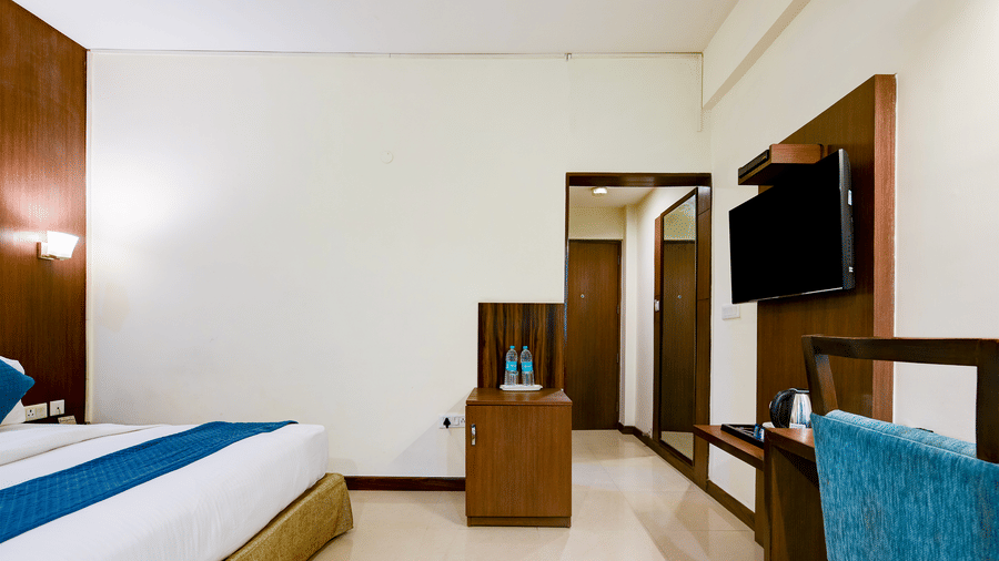 The Pamposh, New Delhi | A room with tables, a chair, a large bed, sporeads, pillows, and doors.