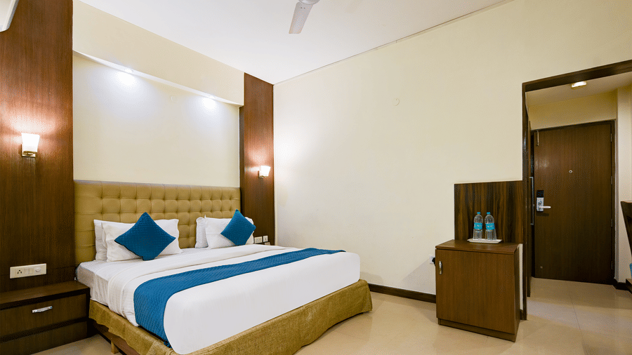 The Pamposh, New Delhi | A room with tables, a chair, a large bed, sporeads, pillows, and doors.