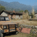 A beige safari jeep parked on a dirt path in front of stone cottages with misty mountains in the background.
