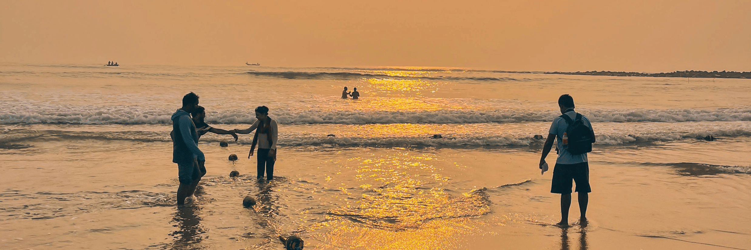 Silhouettes of people standing on a beach during a vibrant sunset.