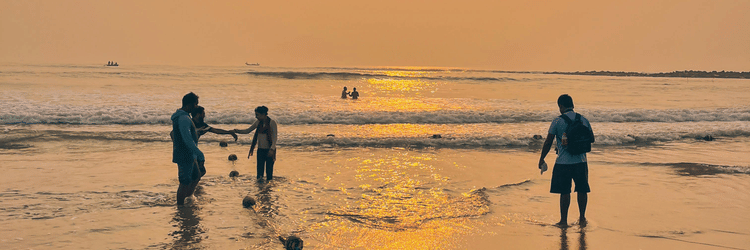 Silhouettes of people standing on a beach during a vibrant sunset.
